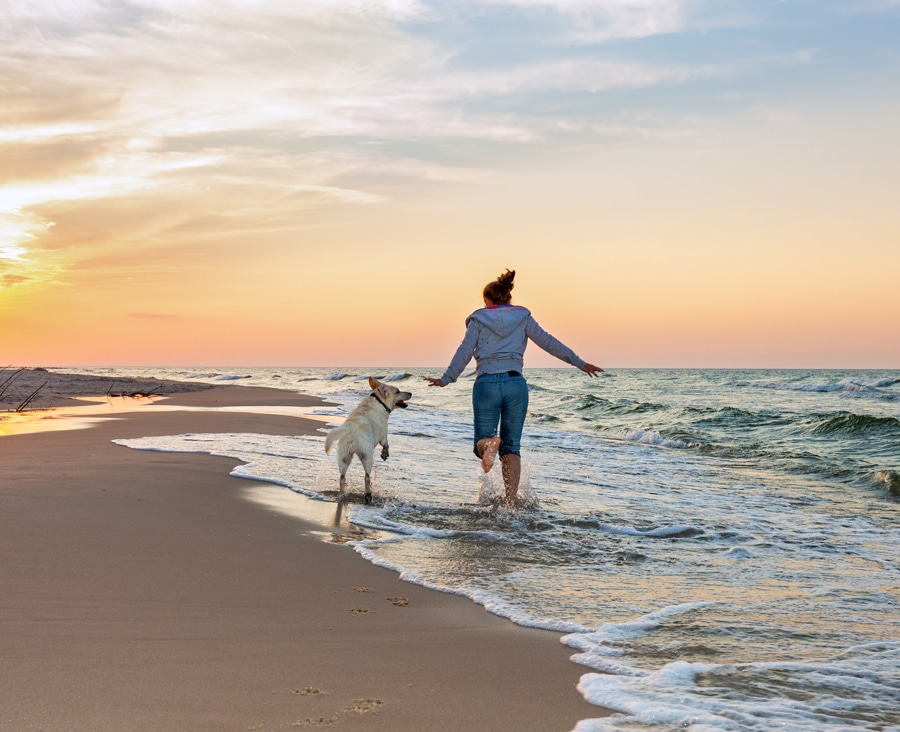 a man walking across a beach next to the ocean